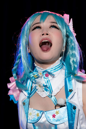Japanese cosplayer Ria Kurumi sings into a microphone and does a blowjob on stage